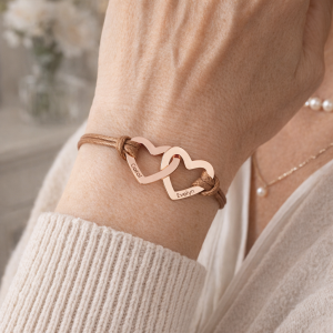 Grandmother wearing personalized engraved bracelet with grandchildren's names on double gold hearts — meaningful grandma gift